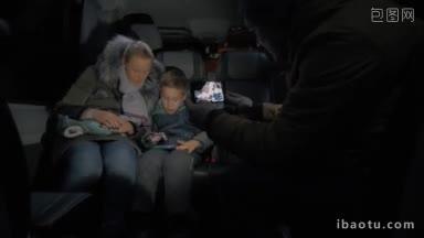 一名男子正在拍摄母子在冬夜乘坐小巴旅行的手机视频，孩子在玩手机